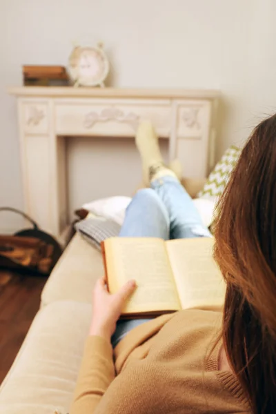 Woman reading book on sofa in room — Stock Photo, Image