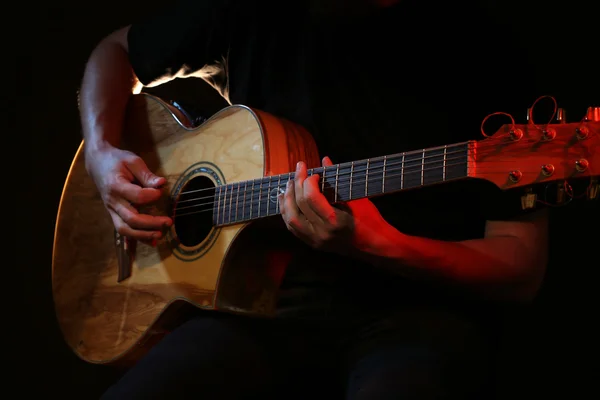 Young man playing on acoustic guitar on dark background — Stock Photo, Image