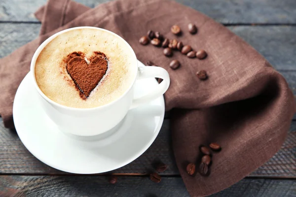 Kopje cappuccino met hart van cacao op houten tafel — Stockfoto