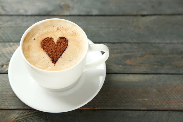 Copa de capuchino con corazón de cacao en mesa de madera — Foto de Stock