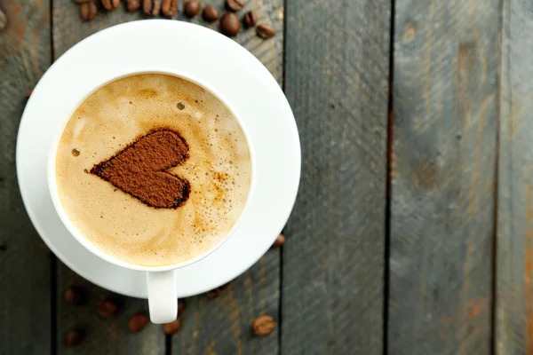 Cup of cappuccino with heart of cocoa on wooden table — Stock Photo, Image