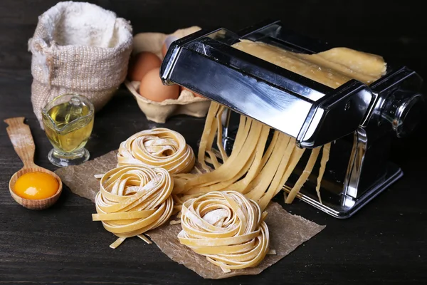 Metal pasta maker machine and ingredients for pasta on wooden background — Stock Photo, Image