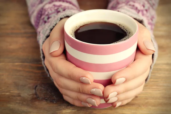 Female hands holding cup of coffee on wooden background — Stock Photo, Image