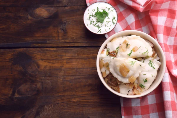 Tasty dumplings with fried onion in brown bowl, on wooden background — Stock Photo, Image