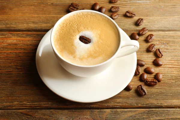 Copa de café latte arte con granos sobre fondo de madera — Foto de Stock