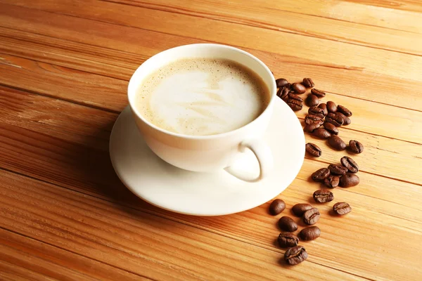 Šálek kávy latte umění s zrna na dřevěné pozadí — Stock fotografie
