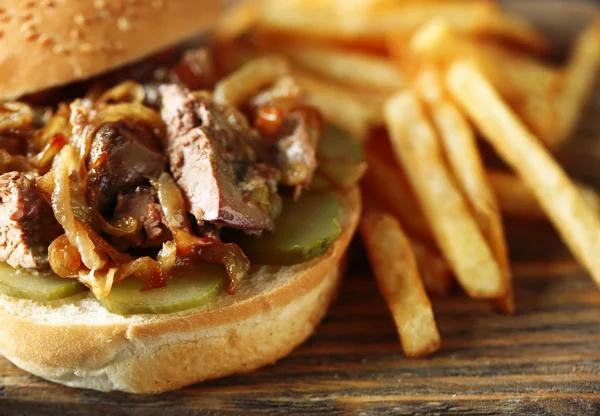 Hambúrguer saboroso e batatas fritas em fundo de mesa de madeira, close-up conceito de comida não saudável — Fotografia de Stock