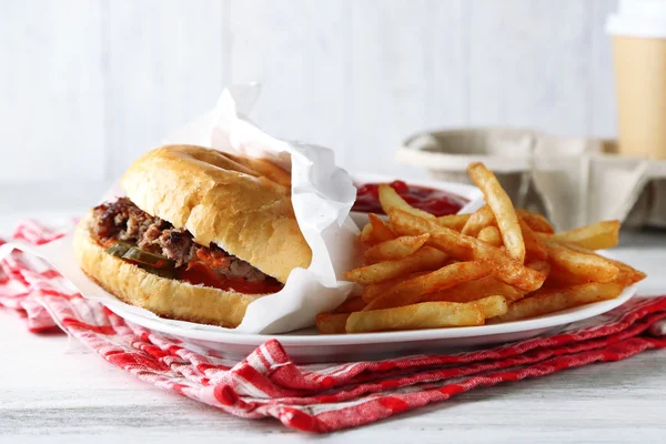 Smaklig hamburgare och pommes frites på tallriken, på träbord bakgrund. Begreppet ohälsosam mat — Stockfoto