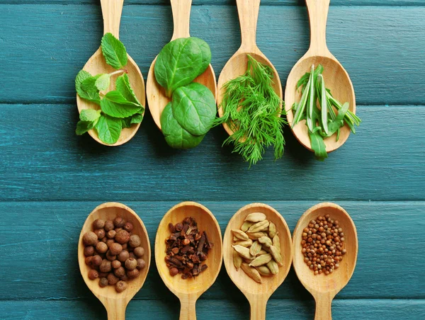 Wooden spoons with fresh herbs and spices on color wooden background — Stock Photo, Image