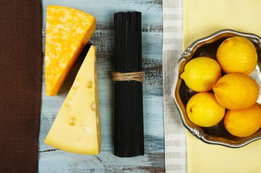 Peynir, siyah spagetti ve ahşap masa üstüne limon görüntüleyin