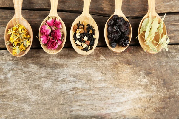 Collection of tea and natural additives in wooden spoons, on old wooden table — Stock Photo, Image