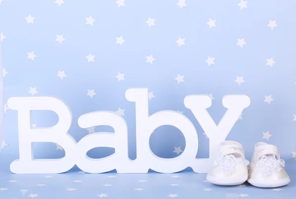 Word baby and booties on blue background — Stock Photo, Image