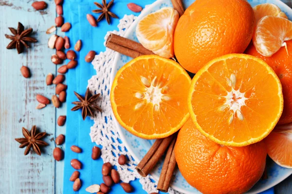 オレンジ色のみかん、ピーナッツ、青い木製のテーブルの上にシナモンスティックを表示します。 — ストック写真