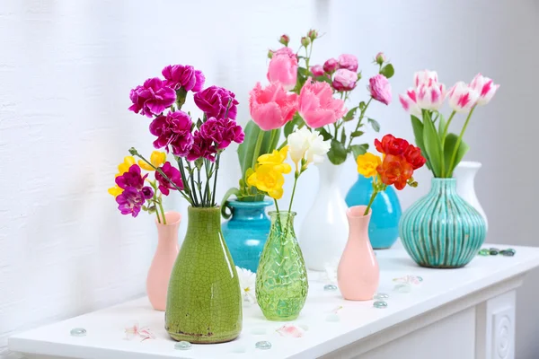 Beautiful composition with different flowers in vases on wall background — Stock Photo, Image