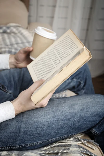 Young man reading book, close-up, on home interior background — Stock Photo, Image