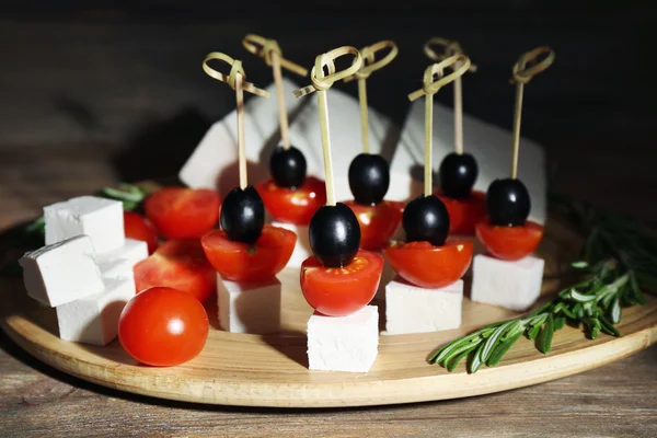 Canapés de queso con tomates cherry y aceitunas en bandeja de madera de cerca —  Fotos de Stock