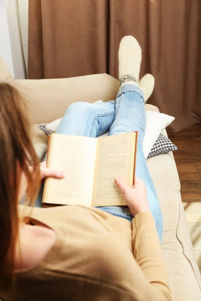 Woman reading book on sofa in room — Stock Photo, Image