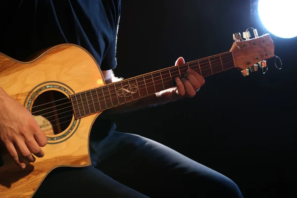 Young man playing on acoustic guitar on dark background — Stock Photo, Image