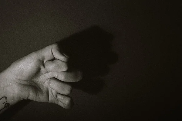 Ombre de la main féminine formant le visage humain sur fond sombre — Photo