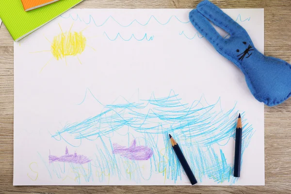 Kids drawing on white sheet of paper with crayons on wooden table, closeup — Stock Photo, Image