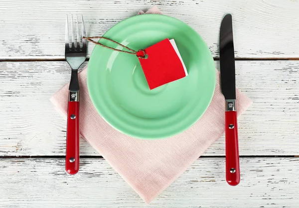 Targhetta bianca su piastra a colori e tovagliolo su tavolo in legno, vista dall'alto — Foto Stock
