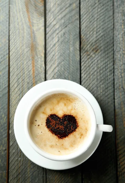 Cup of cappuccino with heart of cocoa on wooden table — Stock Photo, Image