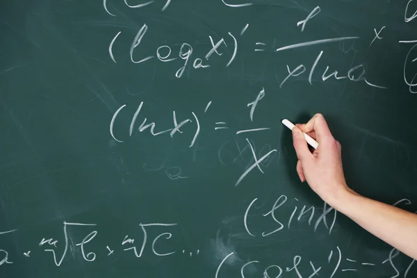 Female hand writing formulas on blackboard with chalk, close up — Stock Photo, Image