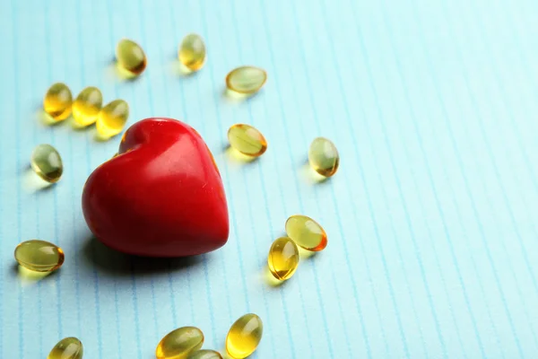 Red heart and cod liver oil, on blue background — Stock Photo, Image