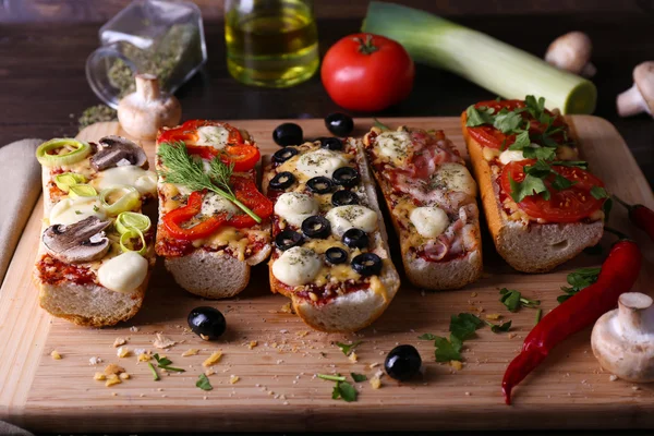 Different sandwiches with vegetables and cheese on cutting board on table close up — Stock Photo, Image