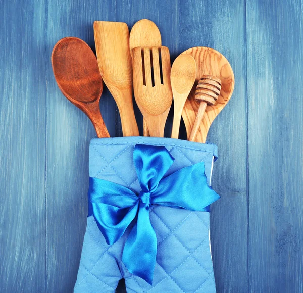 Different kitchen utensils in potholder on wooden background — Stock Photo, Image