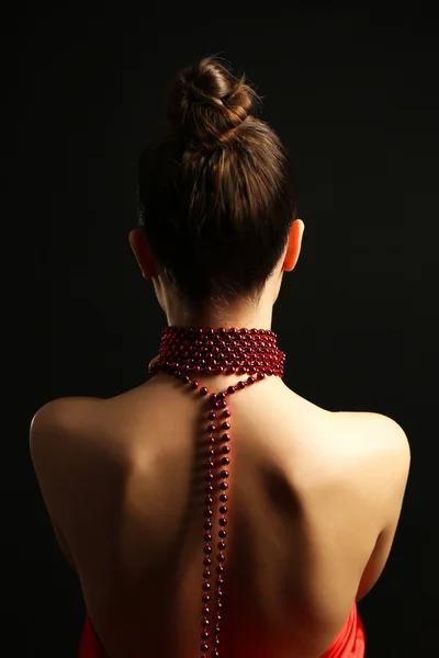 Back of beautiful woman with beads on her neck on dark background — Stock Photo, Image