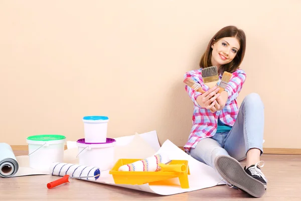 Beautiful girl sitting on floor with equipment for painting wall — Stock Photo, Image