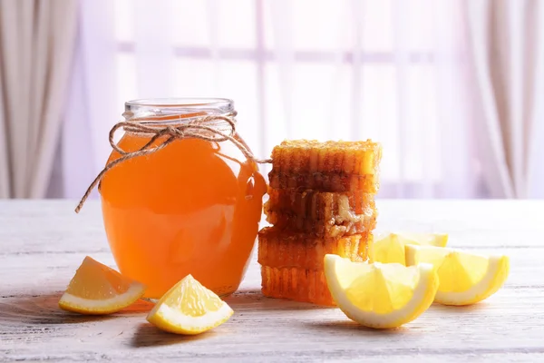 Delizioso miele con limone sul tavolo su sfondo chiaro — Foto Stock