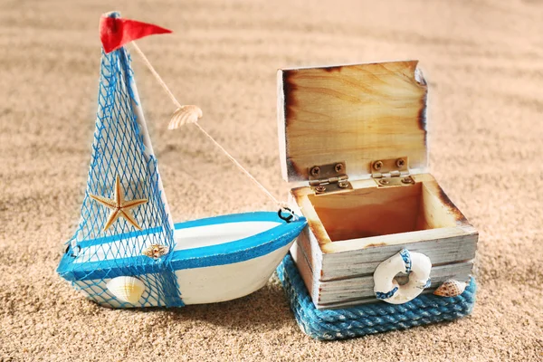 Toy model of ship with wooden box on sea sand background — Stock Photo, Image