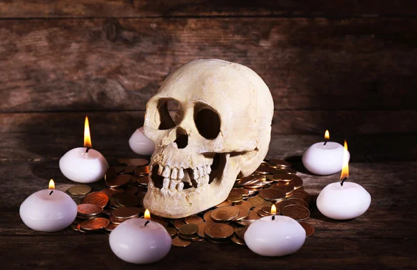 Still life with human skull, candles and gold coins on wooden background — Stock Photo, Image