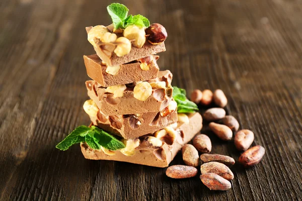 Pilha de chocolate com nozes na mesa de madeira, close-up — Fotografia de Stock