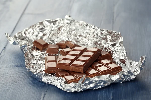 Chocolate en papel de aluminio sobre mesa de madera, primer plano —  Fotos de Stock