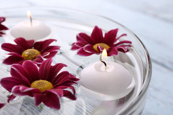 Ciotola di acqua termale con fiori e candele sul tavolo di legno, primo piano — Foto Stock