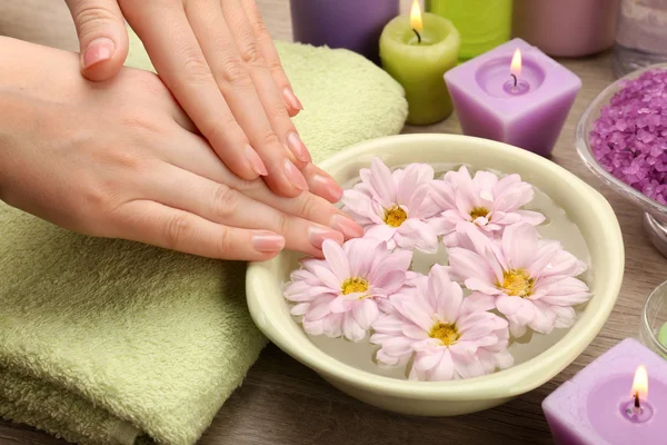 Vrouwelijke handen met kom aroma spa water op houten tafel, close-up — Stockfoto