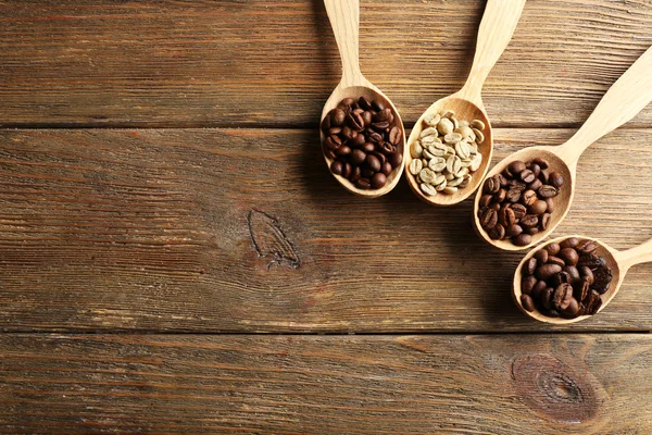 Kaffeebohnen in Löffeln auf Holzgrund — Stockfoto