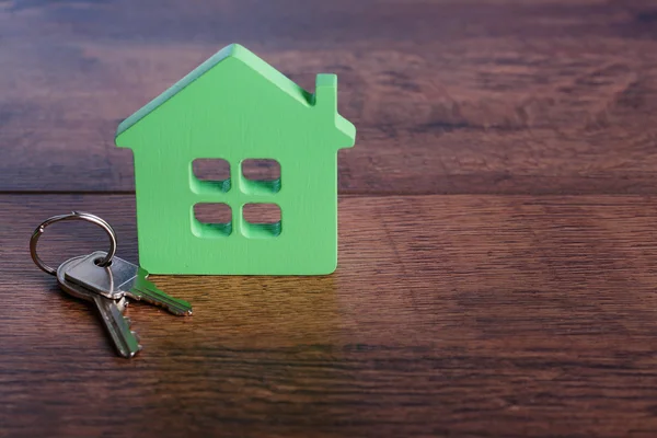 Игрушечный дом с ключом на деревянном фоне — стоковое фото