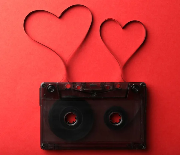 Audio cassette met magnetische tape in de vorm van harten op rode achtergrond — Stockfoto