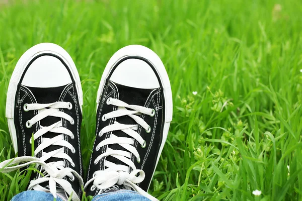 Female feet in gumshoes on green grass background — Stock Photo, Image