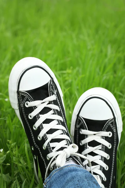 Pies femeninos en zapatos de goma sobre fondo de hierba verde — Foto de Stock