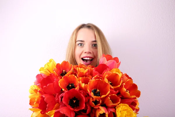 Porträt einer jungen Frau mit schönem Strauß Tulpen auf Tapetenhintergrund — Stockfoto