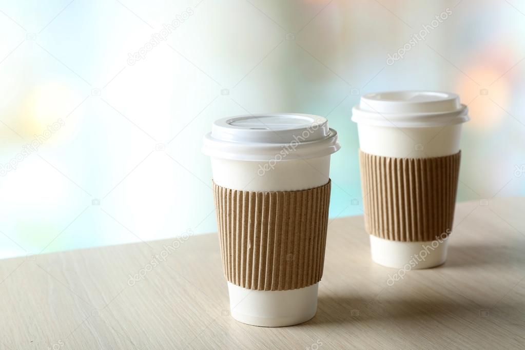 Paper cups of coffee on table on bright background