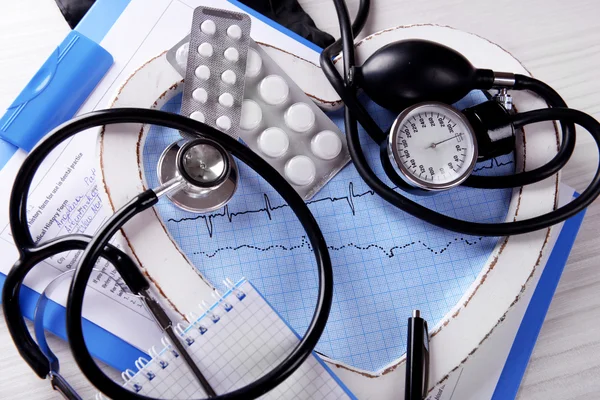 Kardiogramm mit Stethoskop und Pillen auf dem Tisch, Nahaufnahme — Stockfoto