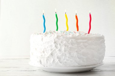 Renkli arkaplanda mumlar olan doğum günü pastası