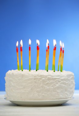 Renkli arkaplanda mumlar olan doğum günü pastası