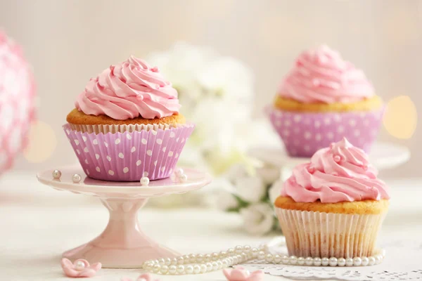 Deliciosos cupcakes en la mesa sobre fondo claro —  Fotos de Stock